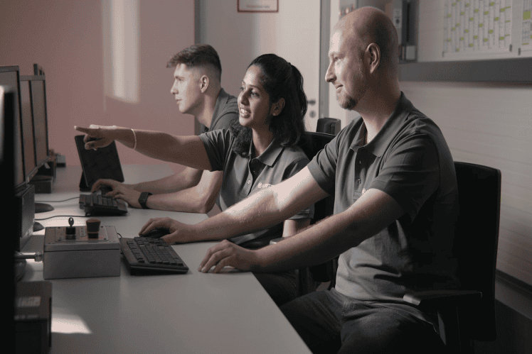 Drei Mitarbeiter von ZF Lifetec arbeiten an Computern in einem Büro.