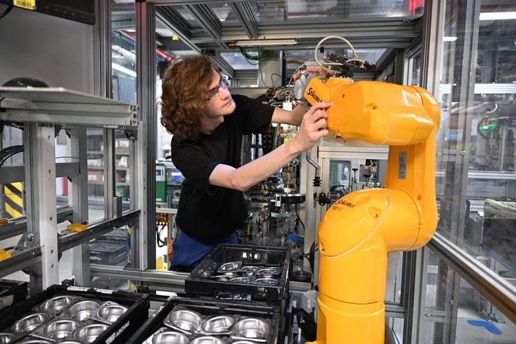 Mitarbeiterin bei ZF Lifetec bedient Industrieroboter