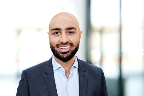 Mann mit Glatze und Bart, professionell gekleidet, lächelt