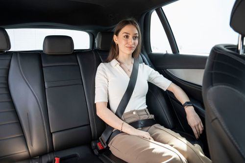 Frau sitzt angeschnallt auf Rückbank eines Autos